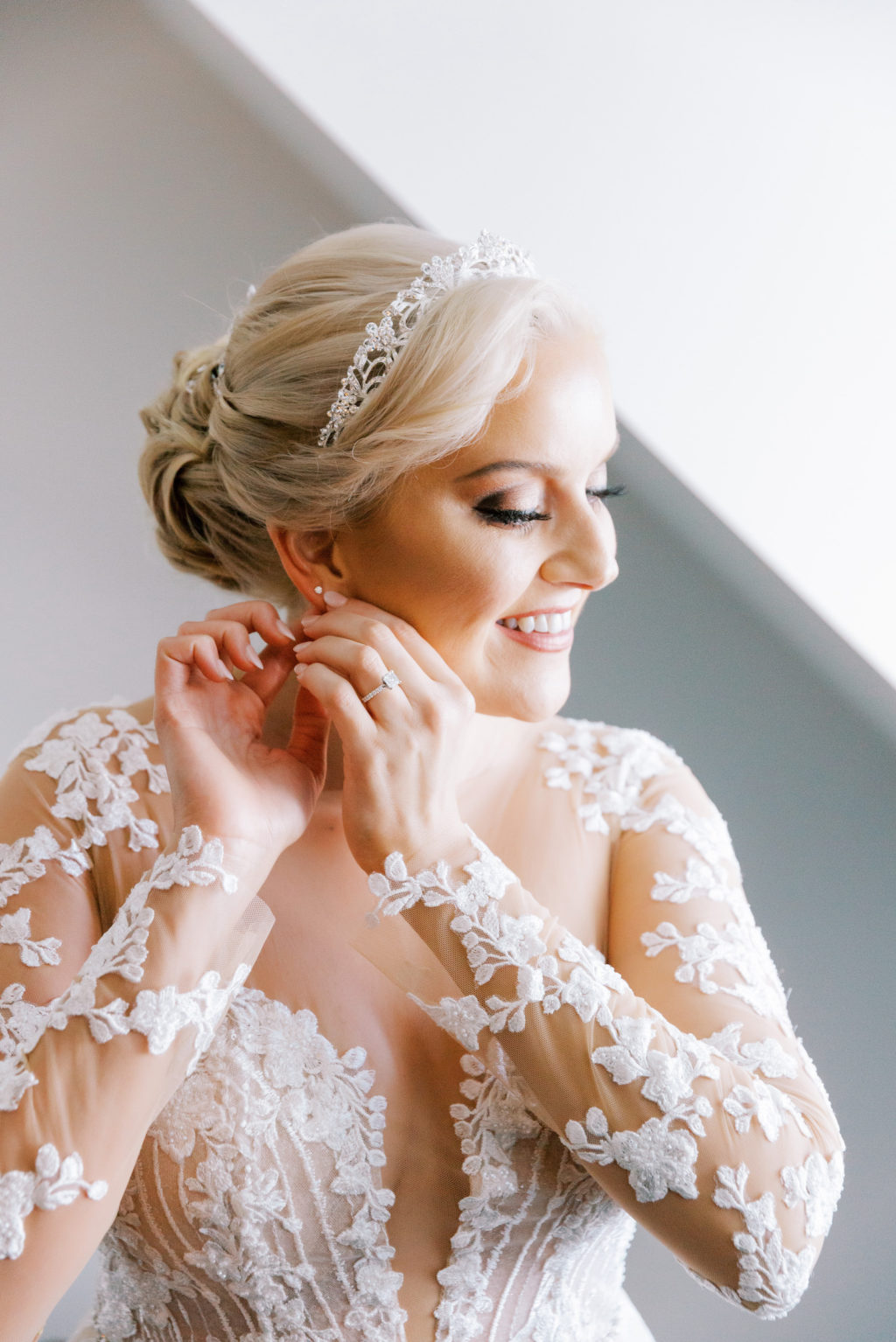Tampa Bay Bride Getting Ready, Wearing Rhinestone Tiara, Romantic Adam Zohar A-Line Wedding Dress with Illusion Neckline and Lace Sleeve Detailing | Florida Wedding and Bridal Boutique Isabel O'Neil Bridal Collection
