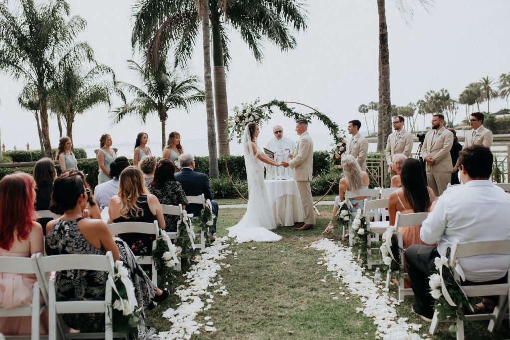 Earthy Elegant Wedding Ceremony Decor, Bride and Groom Exchanging Wedding Vows, Circular Arch with Greenery Garland, White and Blush Pink Flowers | Tampa Bay Wedding Dress Shop Truly Forever Bridal