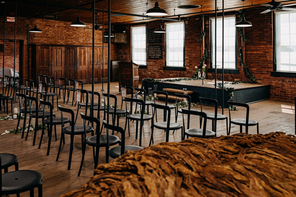 Vintage Inspired Tampa Bay Wedding Ceremony Decor, Simplisitic Brick Exposed Industrial venue, Metal Black Chairs, decorated with Candles, White Rose Petals, and Greenery, Ivy and Vines Wrapped Around Staircase | Unique Florida Wedding Venue J.C. Newman Cigar Co. in Ybor City