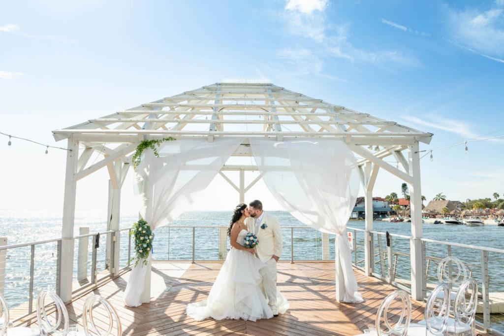 Waterfront Wedding Ceremony with Overwater Pier and White Pergola with Draping and Greenery | Tampa Wedding Venue The Godfrey