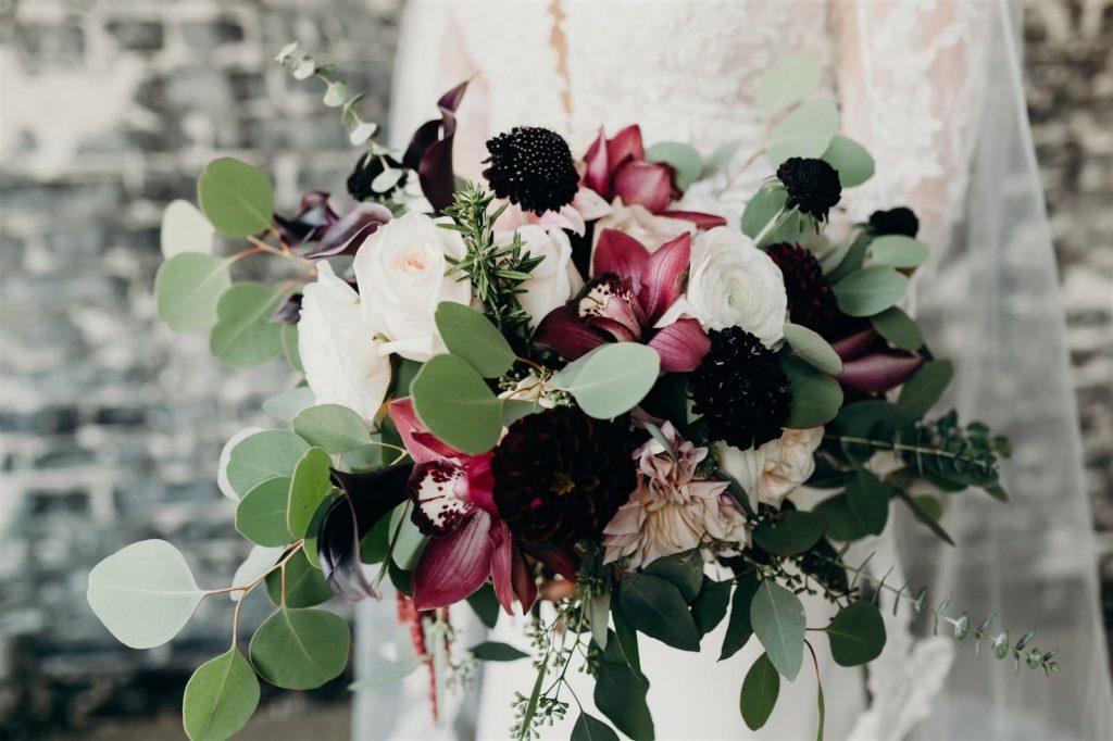 Fall Winter Wedding Bouquet with Loose Eucalyptus Greenery, White Roses, Scabiosa, Deep Red Orchids, Ranunculus, Zinnia, and Amaranthus | Botanica International Design