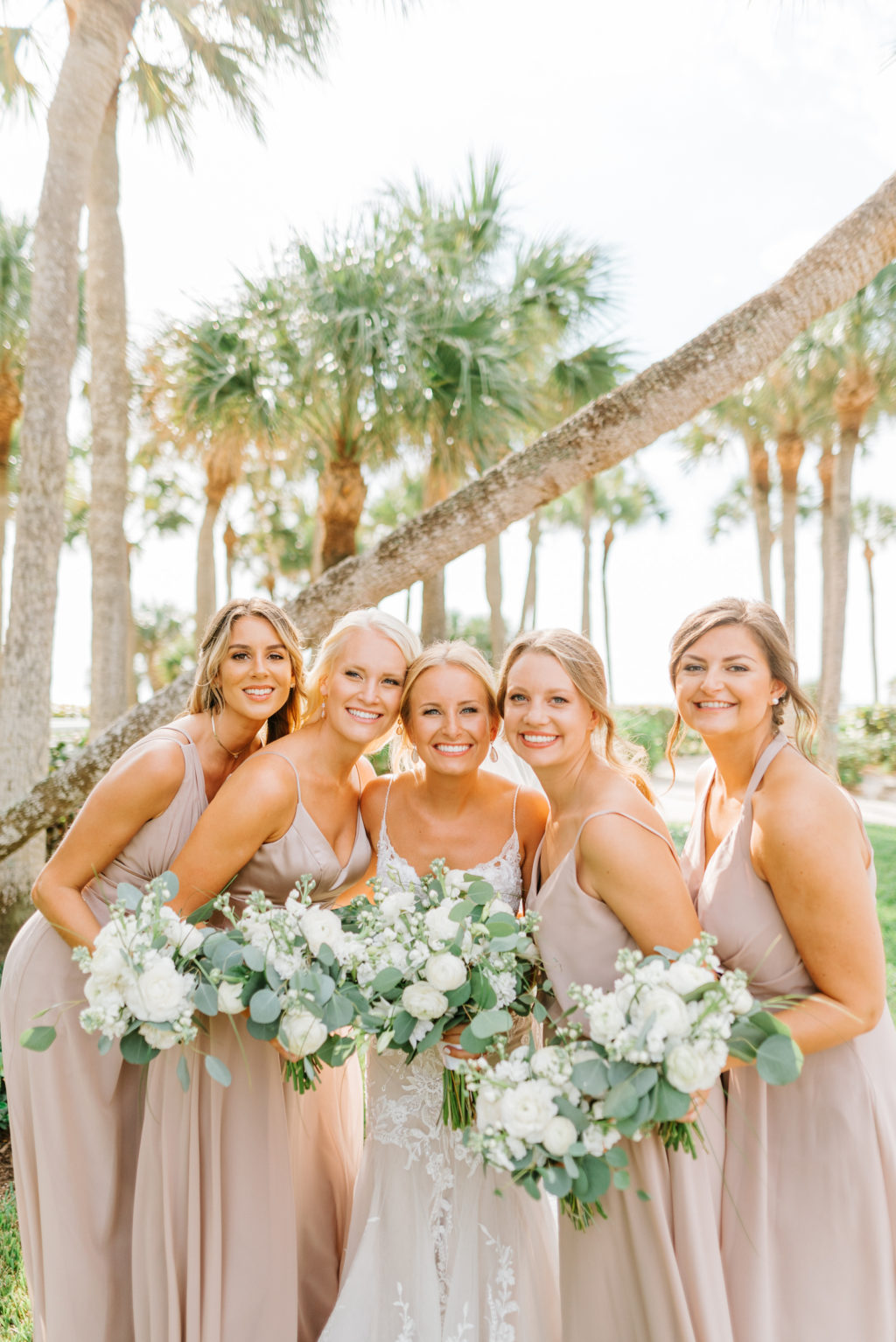 Natural Classic Bride in Romantic Spaghetti Strap Lace Wedding Dress and Bridesmaids in Dusty Rose, Mauve Dresses Holding White Roses and Eucalyptus Greenery Floral Bouquets