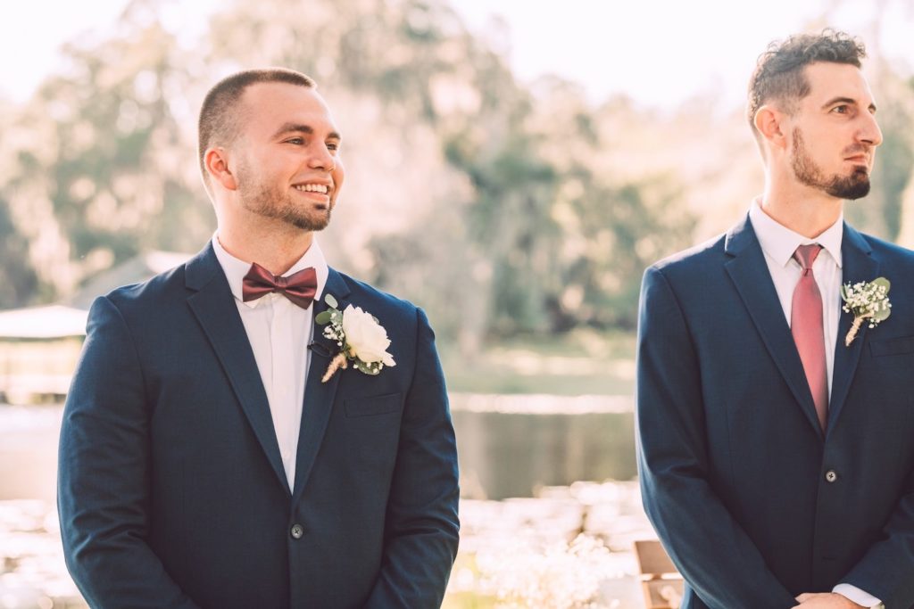 Florida Groom Happy Reaction to Watching Bride Walking Down the Wedding Ceremony Aisle Wearing Burgundy Bowtie and Navy Blue Suit | Tampa Bay Wedding Photographer Bonnie Newman Creative