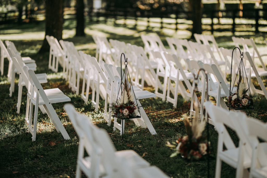 Rustic Wedding Ceremony Decor, White Folding Chairs, Blush Pink and Burgundy Red with Greenery and Dried Leaves Hanging Floral Arrangement