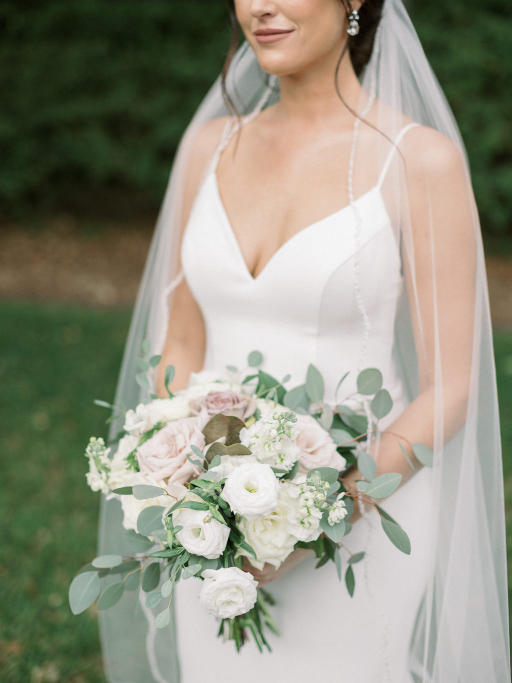 Classic Bride Wearing Paloma Blanca Spaghetti Strap V Neckline Fit and Flare Wedding Dress Holding White and Mauve Roses, Eucalyptus Floral Bouquet
