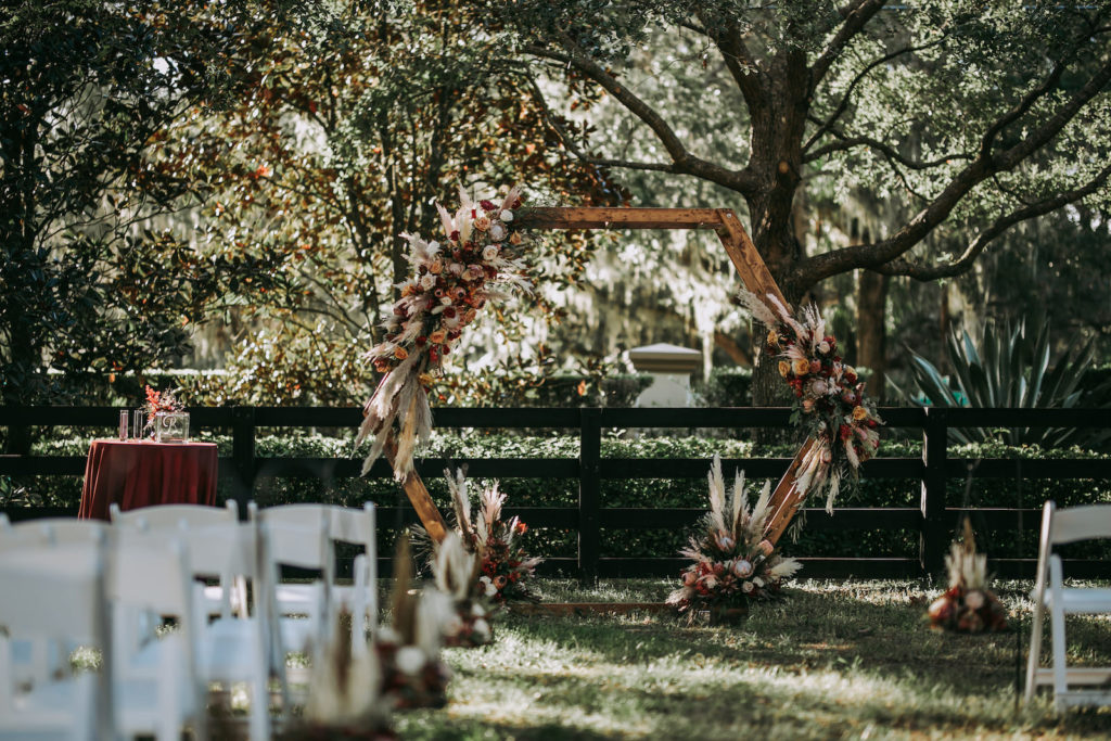 Rustic Wedding Ceremony Decor, Wooden Hexagonal Arch with Lush Floral Arrangements, Pampas Grass, Ivory, Blush Pink and Burgundy Roses | Tampa Wedding Venue Mision Lago Estate
