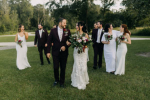 Dark and Moody Bride Holding Garden Inspired Floral Bouquet with Greenery, Pink King Proteas, Red and Ivory Flowers, Groom in Dark Red Suit and Floral Pattern Tie, Bridesmaids in Mix and Match White Dresses, Groomsmen in Maroon Suits | Tampa Bay Wedding Photographer Amber McWhorter Photography | Wedding Florist Brides & Blooms
