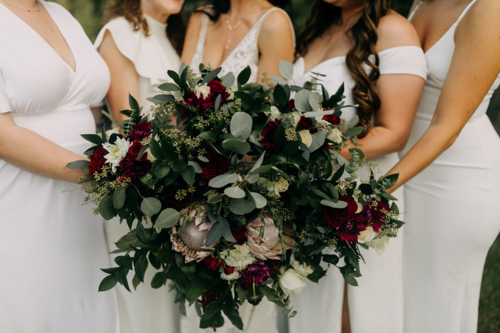 Bride and Bridesmaids Holding Dark and Moody Inspired Floral Bouquets, Greenery, Pink King Proteas, White and Dark Red Flowers | Tampa Bay Wedding Photographer Amber McWhorter Photography | Wedding Florist Brides & Blooms