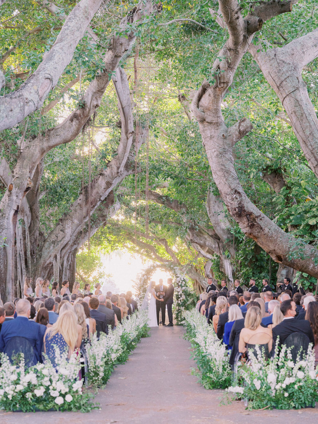 Classic Luxurious Elegant Florida Wedding Ceremony Under Banyan Trees Outdoor, Lush White and Greenery Floral Arrangements and Semi Circle Arch | Boca Grande Wedding Venue The Gasparilla Inn and Club