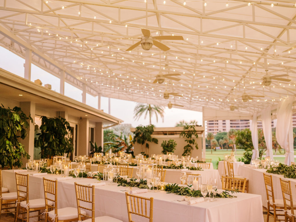 Romantic Elegant Outdoor Courtyard Golf Course Wedding Reception Decor, String Lights, Long Tables with White Linens, Greenery Garland Table Runner, Gold Chiavari Chairs, Candlesticks | Sarasota Waterfront Wedding Venue The Resort at Longboat Key Club