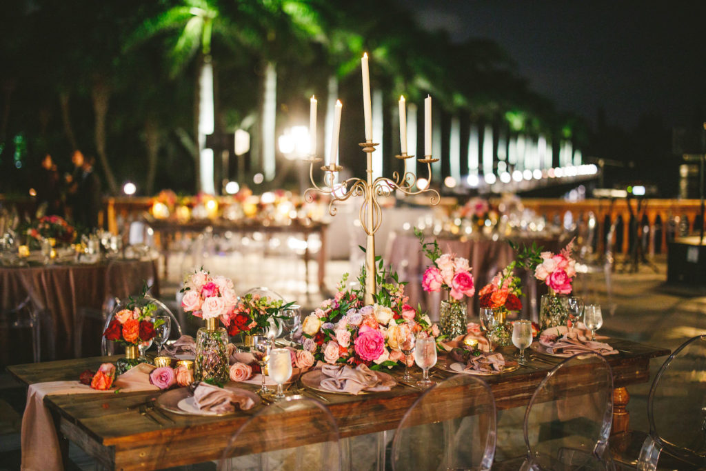 Luxury Elegant Tampa Wedding Reception with Long Wood Feasting Tables featuring Tall Candelabras and Colorful Peach, Blush Pink, Fuchsia and Orange Rose Centerpieces with Greenery and Candles