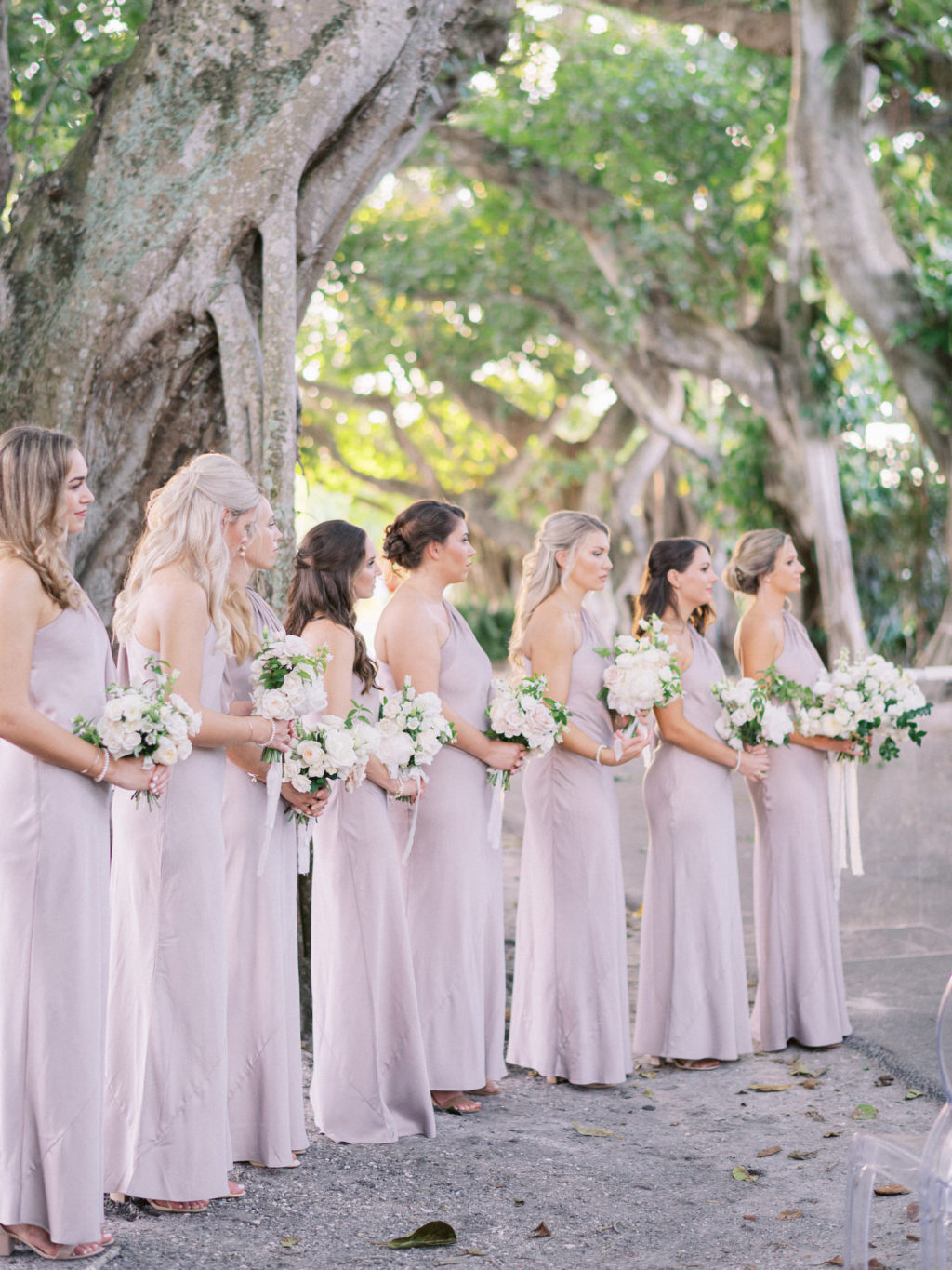 Classic Elegant Florida Bridesmaids Wearing Matching One Shoulder Gray Dresses Holding White Floral Bouquets