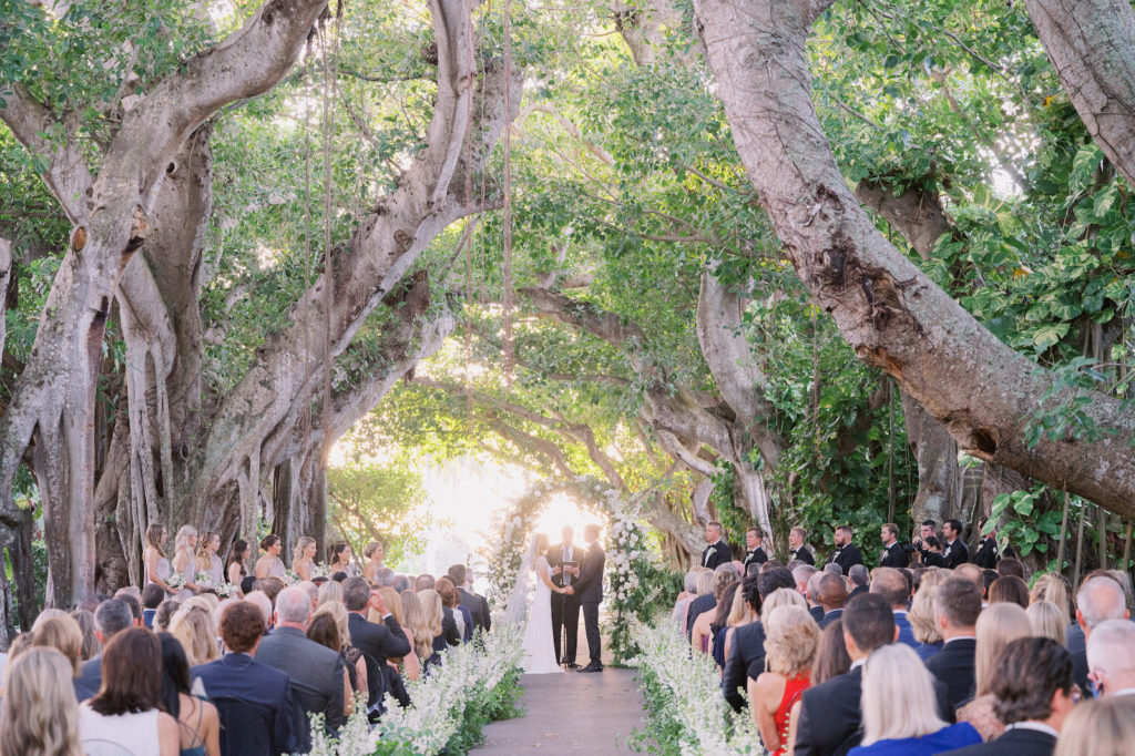 Classic Florida Bride and Groom Exchanging Wedding Vows Lush White Floral and Greenery Leaves Semi Circle Arch | Boca Grande Wedding Venue The Gasparilla Inn and Club