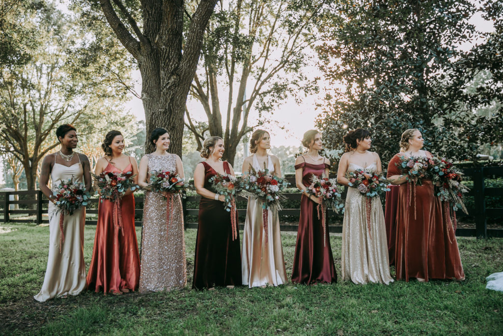 Bridesmaids in Mismatched Champagne, Burnt Orange and Burgundy Dresses Holding Lush Rustic Floral Bouquets During Outdoor Wedding Ceremony | Bella Bridesmaid