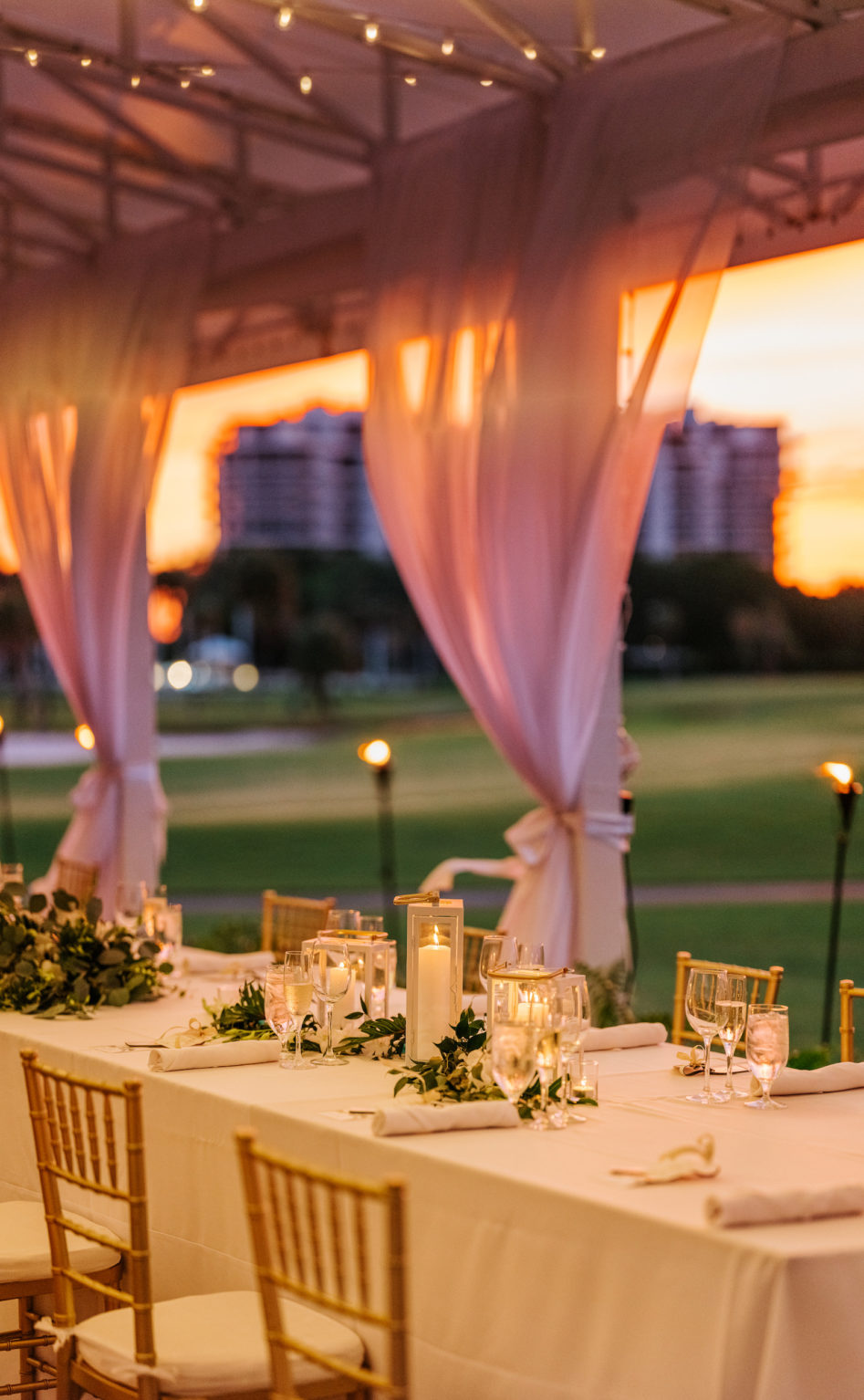 Romantic Elegant Outdoor Courtyard Golf Course Wedding Reception Decor, String Lights, Long Tables with White Linens, Simple Greenery Centerpieces Table Runner, Gold Chiavari Chairs, Candlesticks | Sarasota Waterfront Wedding Venue The Resort at Longboat Key Club