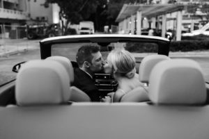 Romantic Black and White Wedding Photo of Bride and Groom Kissing in Getaway Car