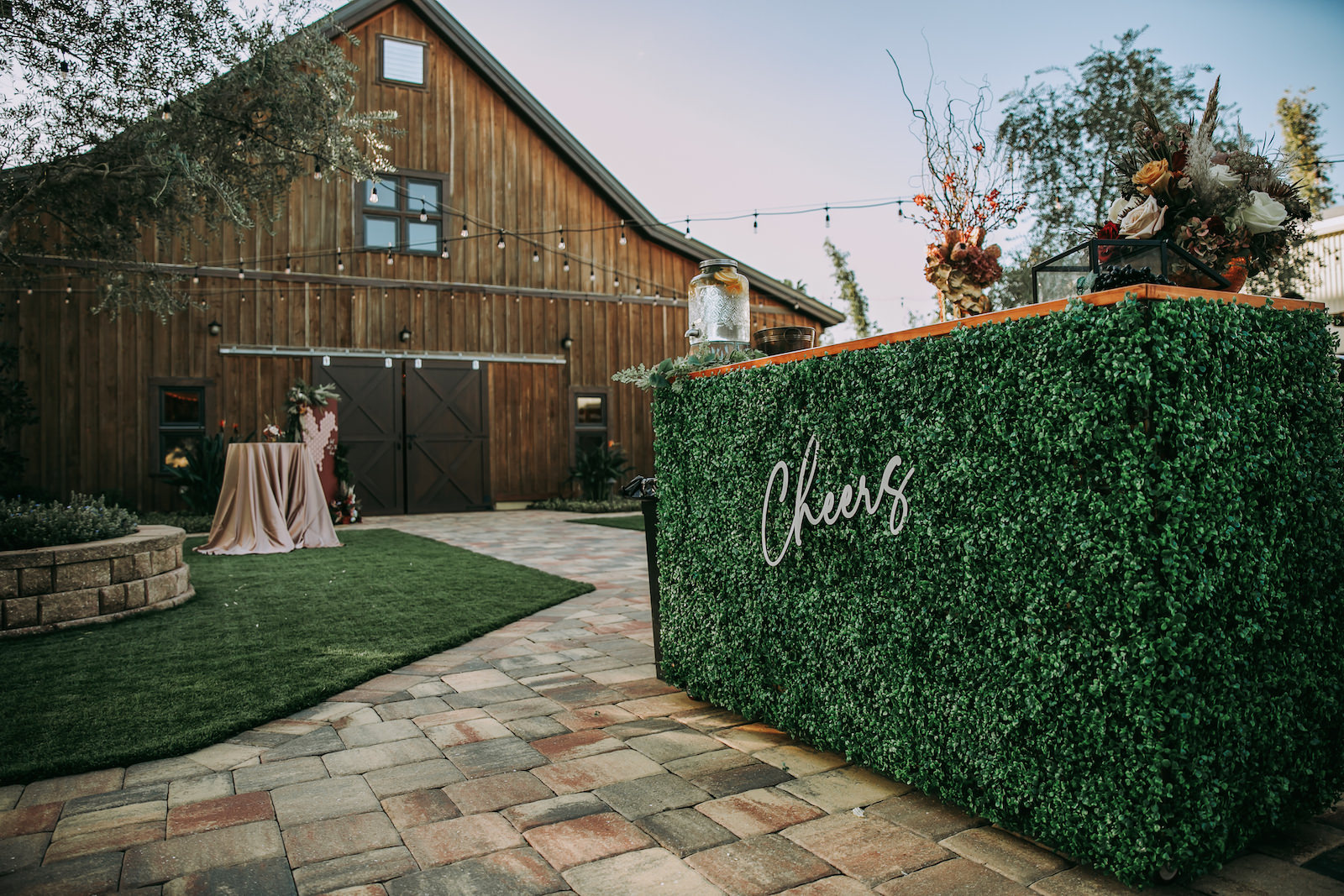 Rustic Barn Wedding Reception Decor, String Lights, Hedge Greenery Wall Bar with Laser Cut "Cheers", Lush Floral Arrangements | Tampa Bay Outdoor Wedding Venue Mision Lago Estate | Mision Lago Ranch