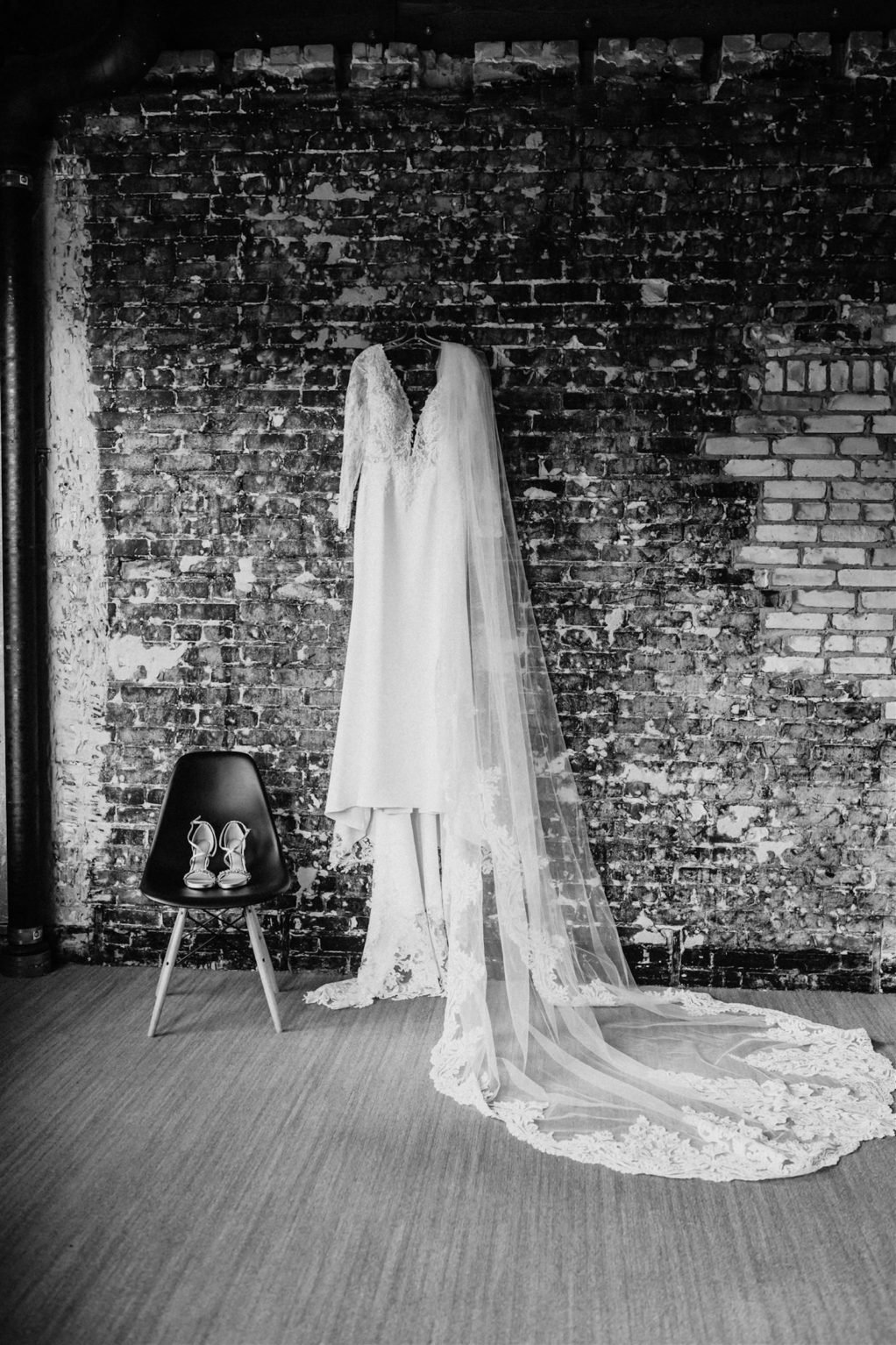 Black and White Photography Wedding Dress Hanger Shot on Brick Wall | V Neck Long Sleeve Lace Sheath Bridal Gown with Lace Trim Edge Cathedral Length Long Veil