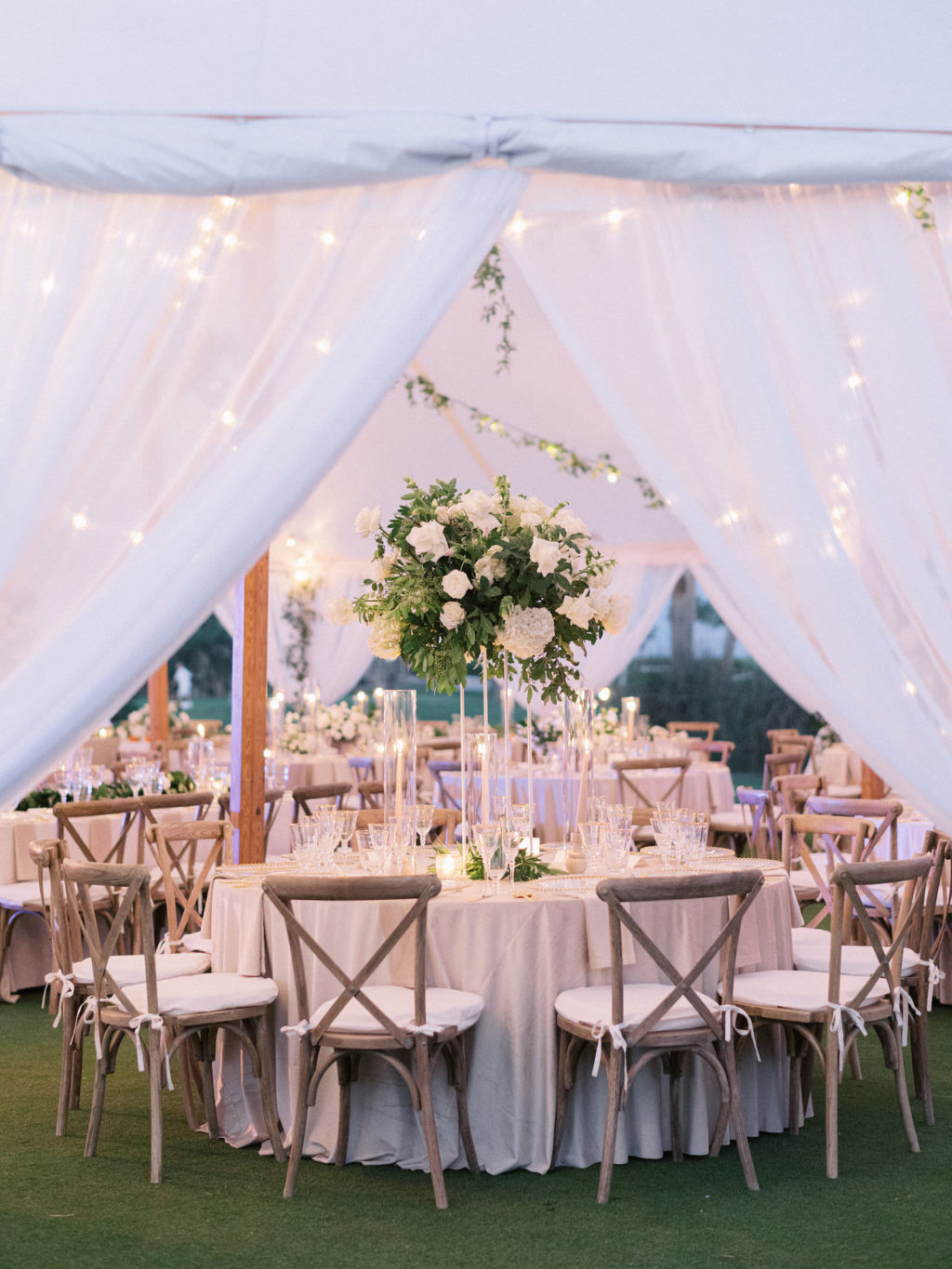 Luxurious Elegant Classic Florida Outdoor Tent Wedding Reception Decor, White Linen Draping, String Lights, Tall White and Greenery Floral Centerpiece, Wooden Cross Back Chairs