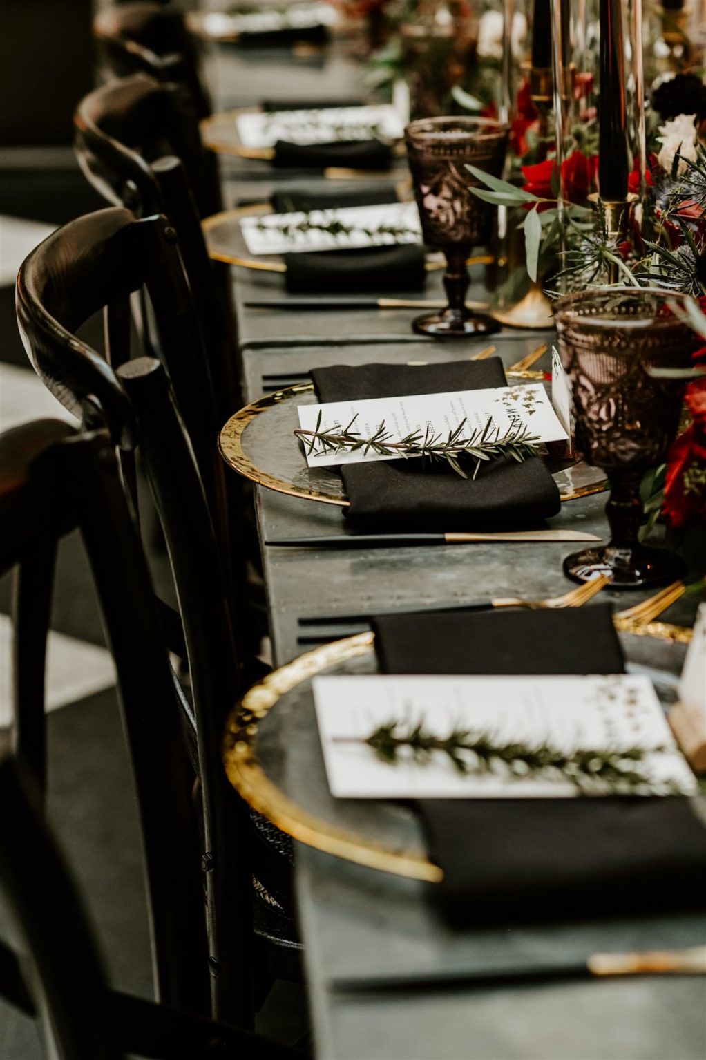Long Communal Banquet Feasting Table Wedding Place Settings with Gold Rim Glass Charger Plates, Black and Gold Flatware, Black Napkins, Menu Cards, and Sprig of Rosemary | Vintage Beaded Goblet Water Wine Glassware by Kate Ryan Event Rentals | Winsor Event Studio