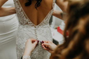 Florida Bride Getting Wedding Ready Putting on Romantic Low Open V Back Lace and Illusion with Button Detail Wedding Dress | Tampa Bay Wedding Photographer Amber McWhorter Photography