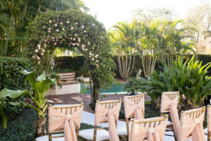 Small Intimate South Tampa Backyard Wedding Ceremony with Greenery Ceremony Arch and Gold Chiavari Chairs with Pink Bow Sashes | Tampa Bay Rental Company Outside the Box Event Rentals