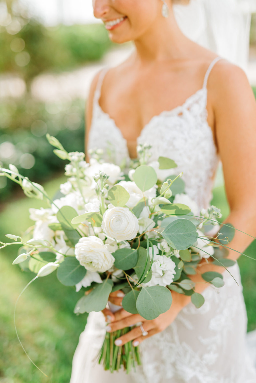 Bride in Romantic Lace Spaghetti Strap Wedding Dress Holding Greenery Eucalyptus and White Roses Floral Bouquet