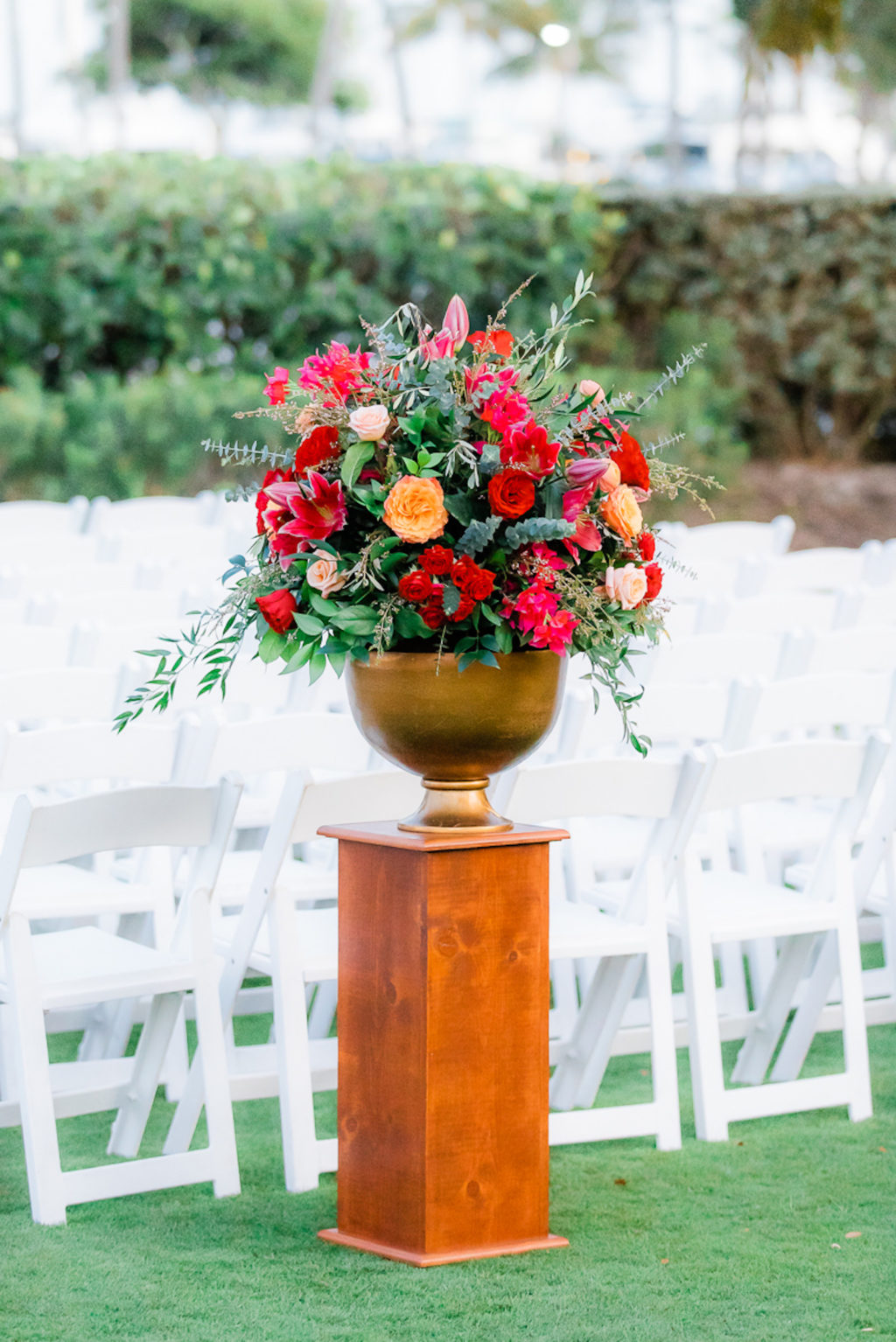 Elegant Wedding Ceremony Decor, Tall Wooden Pedestal, Gold Vase with Jewel Tone Red, Orange, Pink Roses Greenery Floral Arrangement