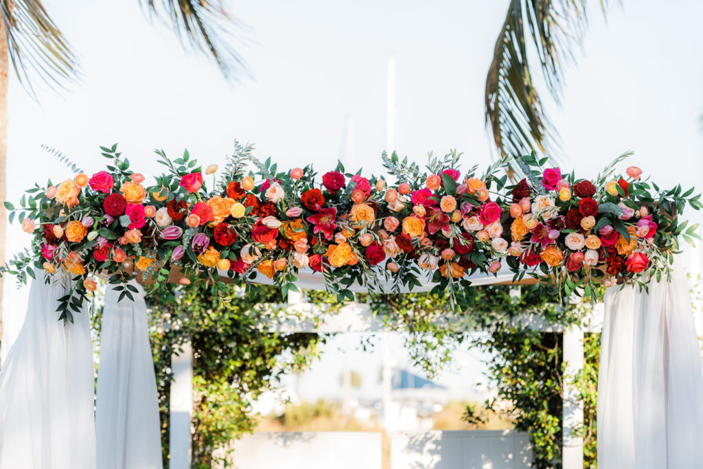 Elegant Wedding Ceremony Decor, Arch with White Linens Jewel Tone Orange, Pink, Red, Purple Roses, Greenery Floral Arrangements