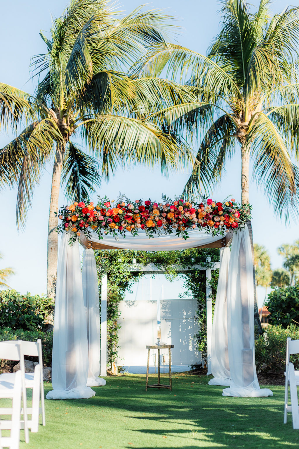 Elegant Wedding Ceremony Decor, Arch with White Linens Jewel Tone Orange, Pink, Red, Purple Roses, Greenery Floral Arrangements