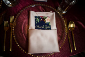 Elegant Wedding Reception Decor, Tabled with Burgundy Linen Tablecloth, Gold Silverware, Gold Beaded and Clear Glass Charger, Blush Pink Linen Napkin with Navy Blue and Floral Thank You Stationery | Tampa Bay Wedding Planner Coastal Coordinating