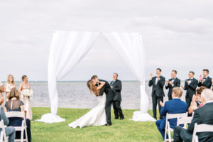 Florida Bride and Groom Exchange First Kiss Under Arch with White Linen Draping Outdoor Waterfront Wedding Ceremony | Tampa Bay Wedding Photographer Kera Photography