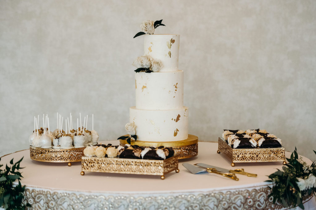 Elegant Three Tier White Wedding Cake with Gold Foil Specks, Ivory Roses, Cake Pops, Cannoli Desserts