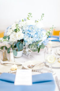 Blue and White Hydrangea Floral Centerpiece with Greenery and Acrylic Table Number | Dusty Blue Napkins | Wedding Reception Decor Ideas