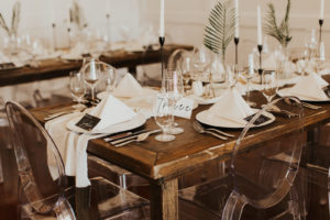 Neutral Timeless Wedding Reception Decor, Long Wooden Feasting Table, Acrylic Ghost Chairs, Simple One Leaf Palm Frond in Vases, Tall Black Candlesticks, Geometric Candle Holders, White Linen Table Runner