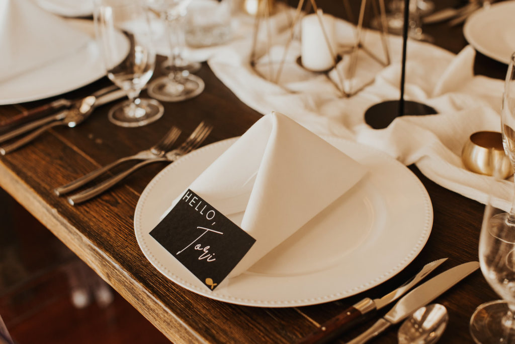 Timeless Neutral Wedding Reception Decor, White Plate with Linen Napkin, Black Name Card on Wooden Table