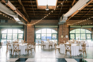 Classic Wedding Reception Decor, Round Tables with White Linens, Wooden Cross Back Chairs, Low Floral Centerpieces, String Lights | Tampa Bay Wedding Photographer Kera Photography | Wedding Caterer Olympia Catering | Wedding Rentals Gabro Event Services | St. Pete Wedding Venue Morean Center for Clay