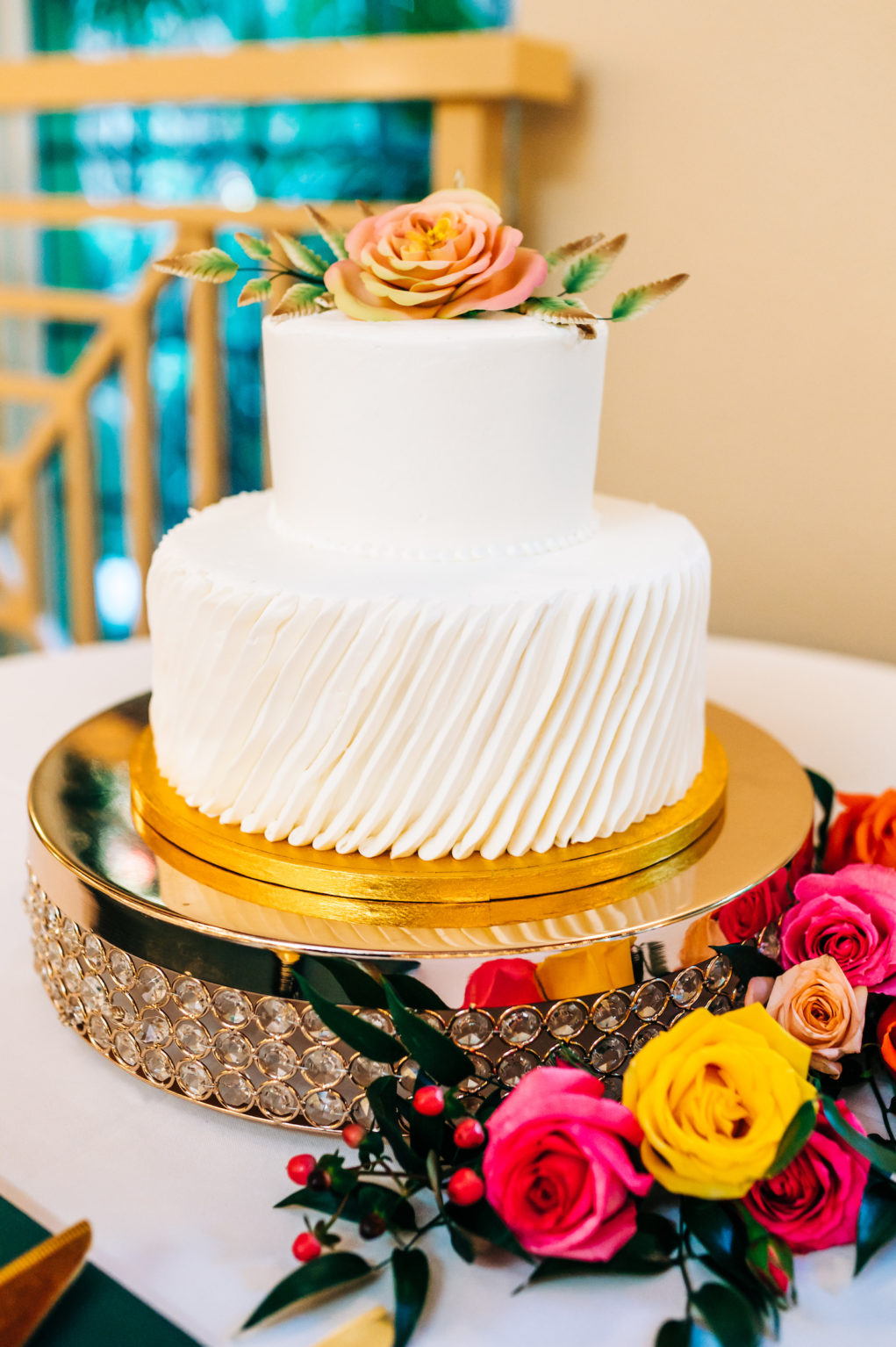 White Two Tiered Wedding Cake with Texture Layer | Gold Cake Stand and Floral Bright Cake Topper