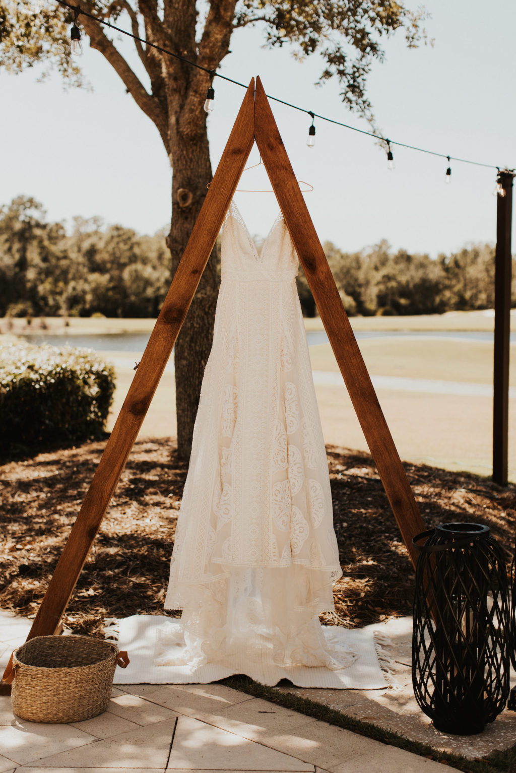 Romantic Flowy Lace Wedding Dress Hanging on Wooden Triangular Arch | Bradenton Wedding Venue The Concession Golf Club