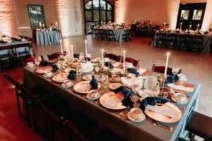 Industrial Indoor Wedding Reception Blue Linens and Wooden Chairs with Candlelit Tablescape | Draping by Florida Gabro Event Rental Services