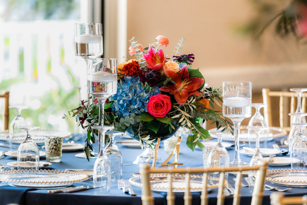 Elegant Wedding Reception Decor, Floating Candlesticks, Low Floral Centerpiece, Blue Hydrangeas, Red and Orange Roses, Pink Tropical Flower, Gold Laser Cut Table Number