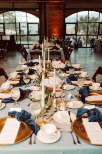 Industrial Indoor Wedding Reception Blue Linens and Wooden Chairs with Candlelit Tablescape | Draping by Florida Gabro Event Rental Services