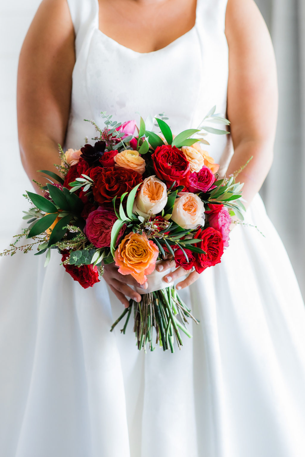 Tampa Bride Wearing A-Line Wedding Dress Scoop Neckline Holding Jewel Tone Pink, Red and Coral Roses with Greenery Floral Bouquet
