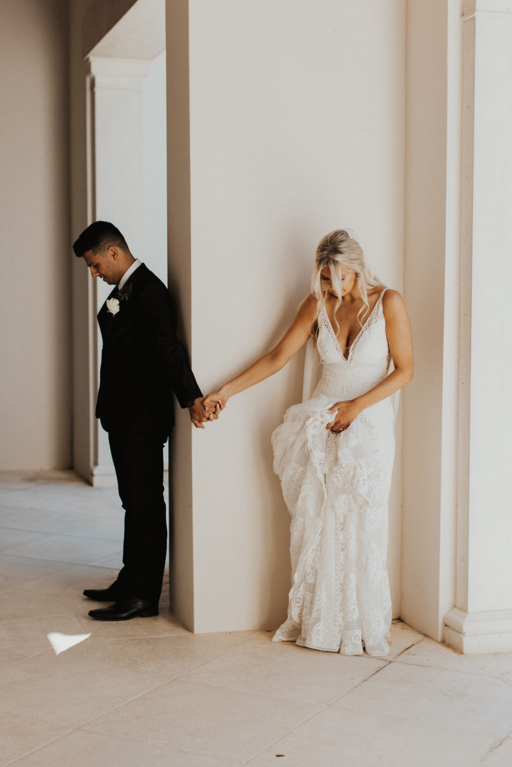 Unique Bride and Groom Holding Hands Behind Wall Secret First Look Wedding Photo