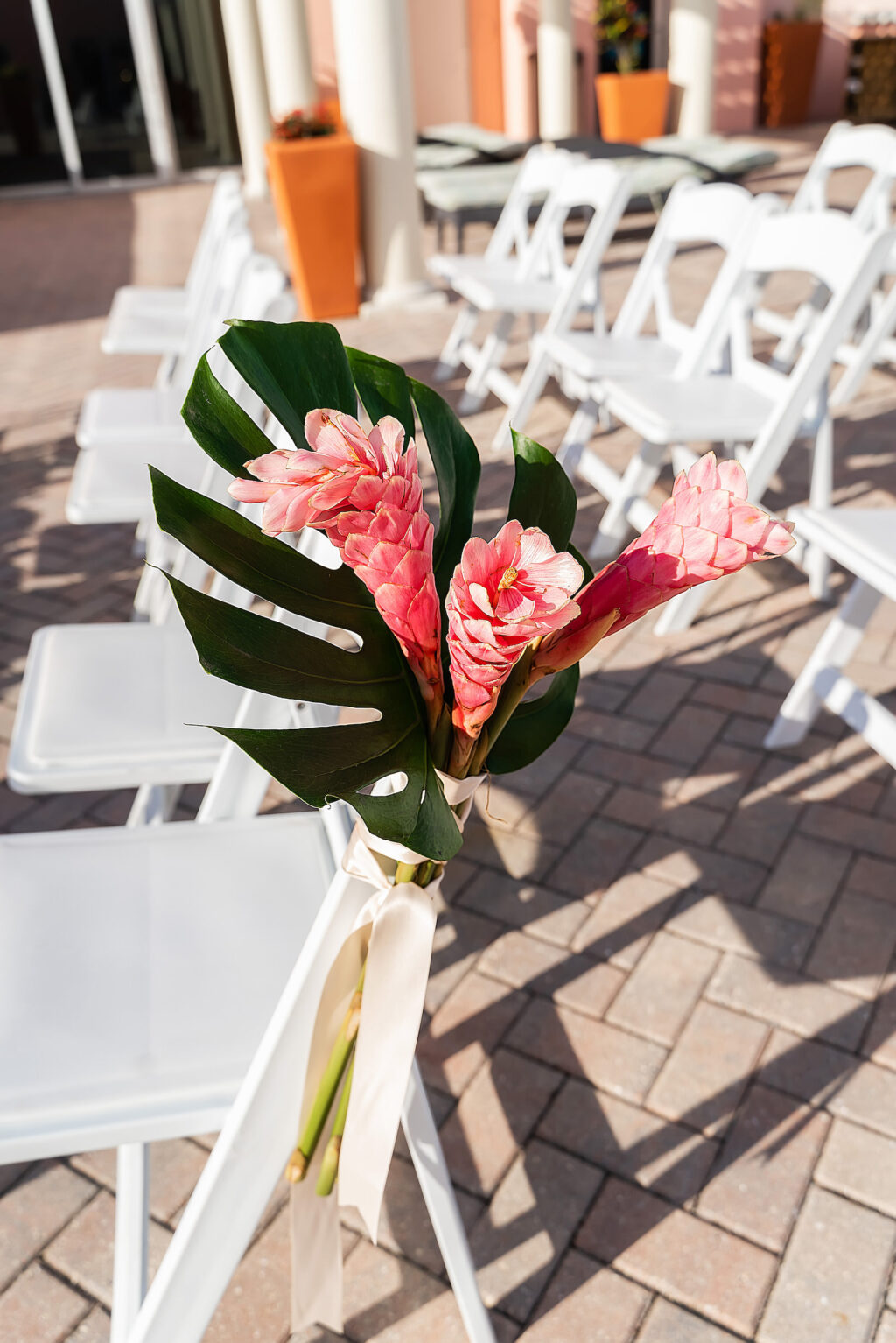 Rooftop Wedding Ceremony Decor, White Patio Folding Chairs, Tropical Monstera Palm Leaf and Pink Ginger Floral Arrangement | Tampa Bay Wedding Photographer Limelight Photography