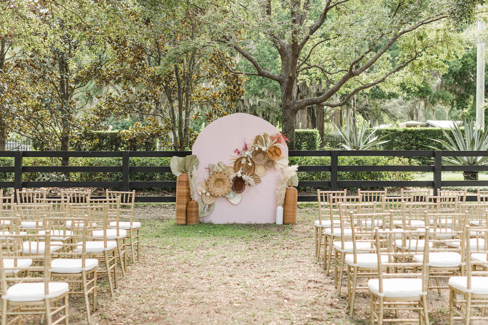 Boho Mid-Century Modern Wedding Ceremony Decor, Wooden Arched Pink Backdrop with Dried Flowers and Leaves, Tall Wooden Vases, Gold Chiavari Chairs | Tampa Bay Wedding Ceremony Backdrop Designer Taylored Affairs | Florida Wedding Venue Mision Lago Estates | Wedding Chair Rentals Kate Ryan Event Rentals
