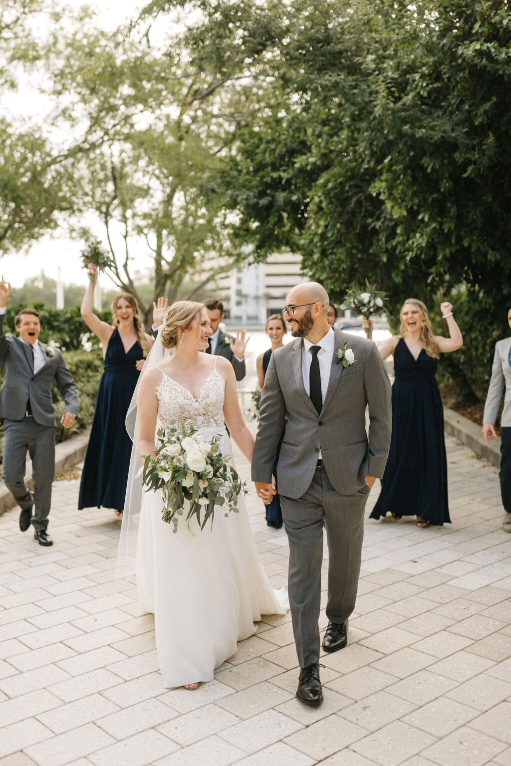 Bride and Groom Outdoor Wedding Party Portrait | Long Chiffon Navy Bridesmaid Dresses | Sheath Satin Charmeuse V Neck Lace Bodice Spaghetti Strap Bridal Gown | Groom and Groomsmen Wearing Classic Charcoal Grey Suit