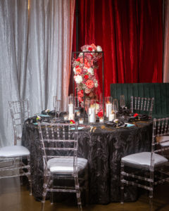 Modern Florida Wedding Reception Decor, Tall Floral Centerpiece with Red Cascading Roses, White Candles, Black Textured Specialty Tablecloth, Teal Menu Stationary, Ghost Chiavari Chairs | Ybor City Venue 7th and Grove