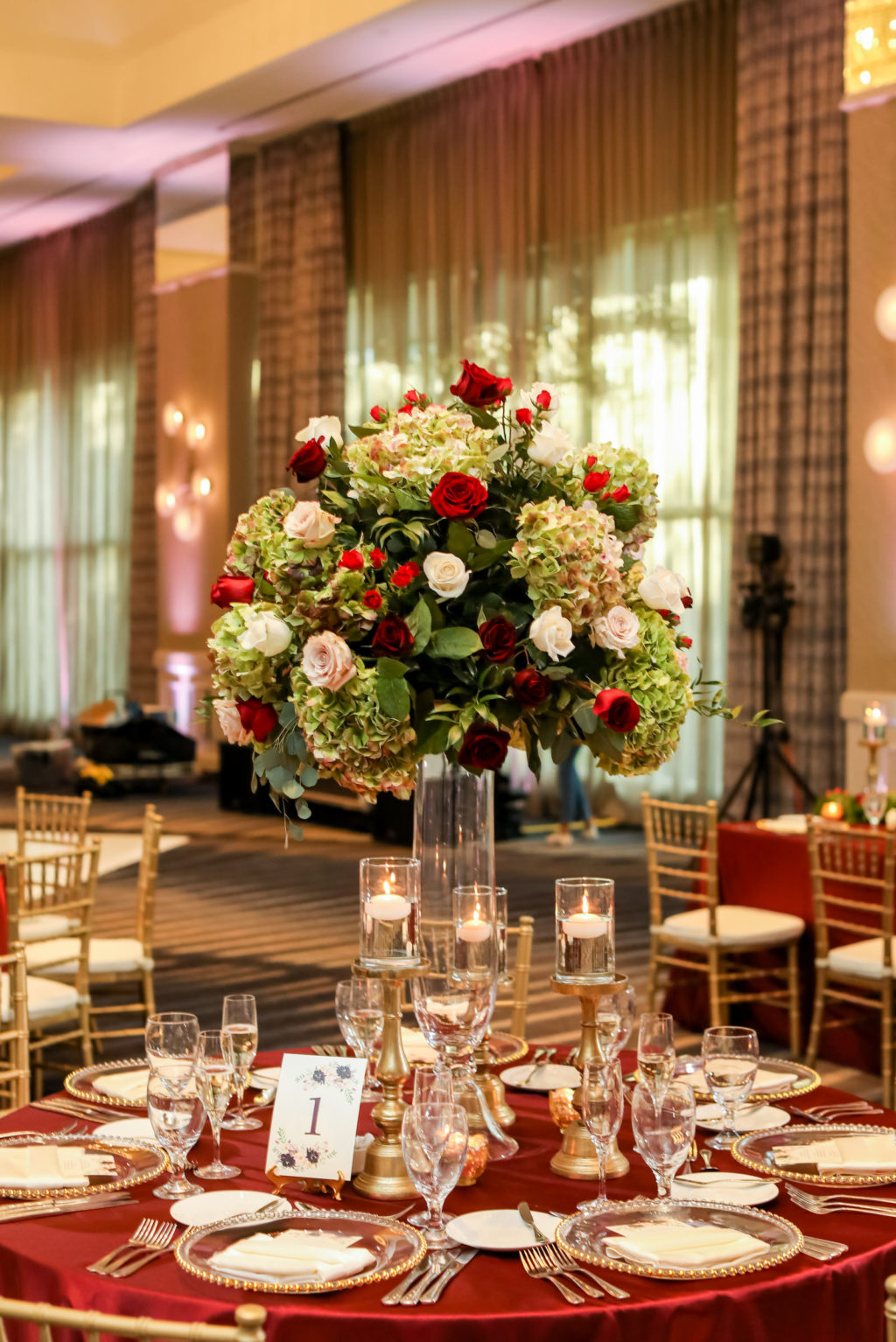 Indian Hindu Wedding Ballroom Reception Decor, Round Table with Burgundy Red Table Linen, Floating Candlesticks, Tall Floral Centerpiece, Green Hydrangeas, Red and White Roses, Gold Chiavari Chairs | Tampa Bay Wedding Photographer Lifelong Photography Studios | Wedding Venue Grand Hyatt Tampa Bay