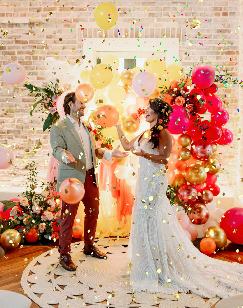 Whimsical and Colorful Bride and Groom Gold Confetti Photo with Orange, Pink, Yellow and Gold Balloon and Fringe Ceremony Backdrop | Tampa Bay Wedding Photographer Dewitt for Love | St. Pete Modern Industrial Wedding Venue Red Mesa Events